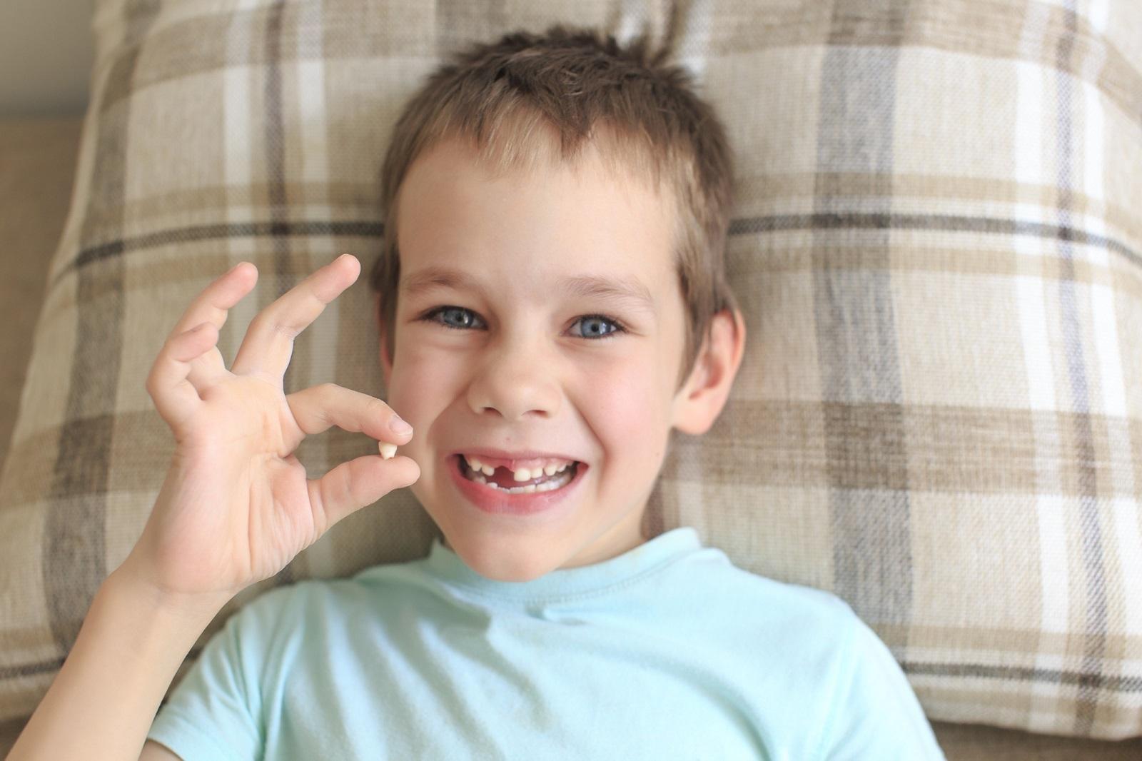 uśmiechniety chłopie z wyrwanym zębem w dłoni