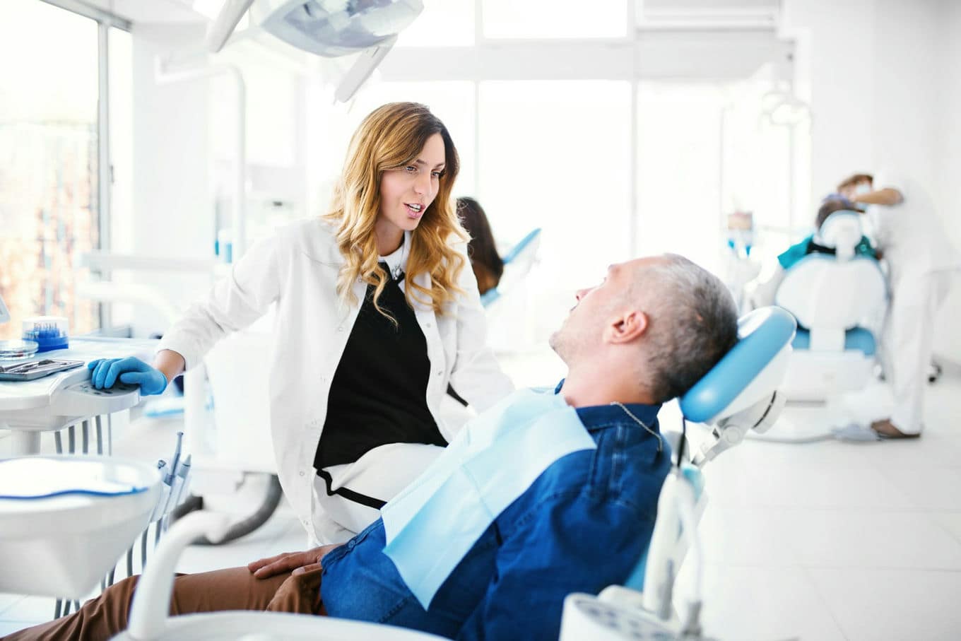 dentystka rozmawia z pacjentem na fotelu