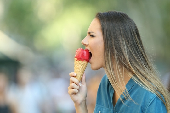 kobieta jedząca loda i cierpiąca na nadwrażliwość zębów