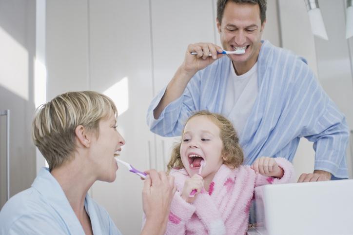 mężczyzna kobieta i dziewczynka myjąca zęby 